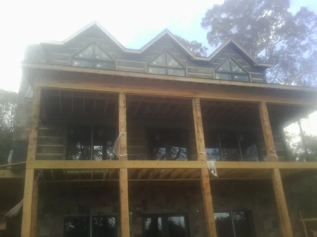 Dormers and porch framing on a large log home under construction — Roof Coating work by our crew in Lake Helen