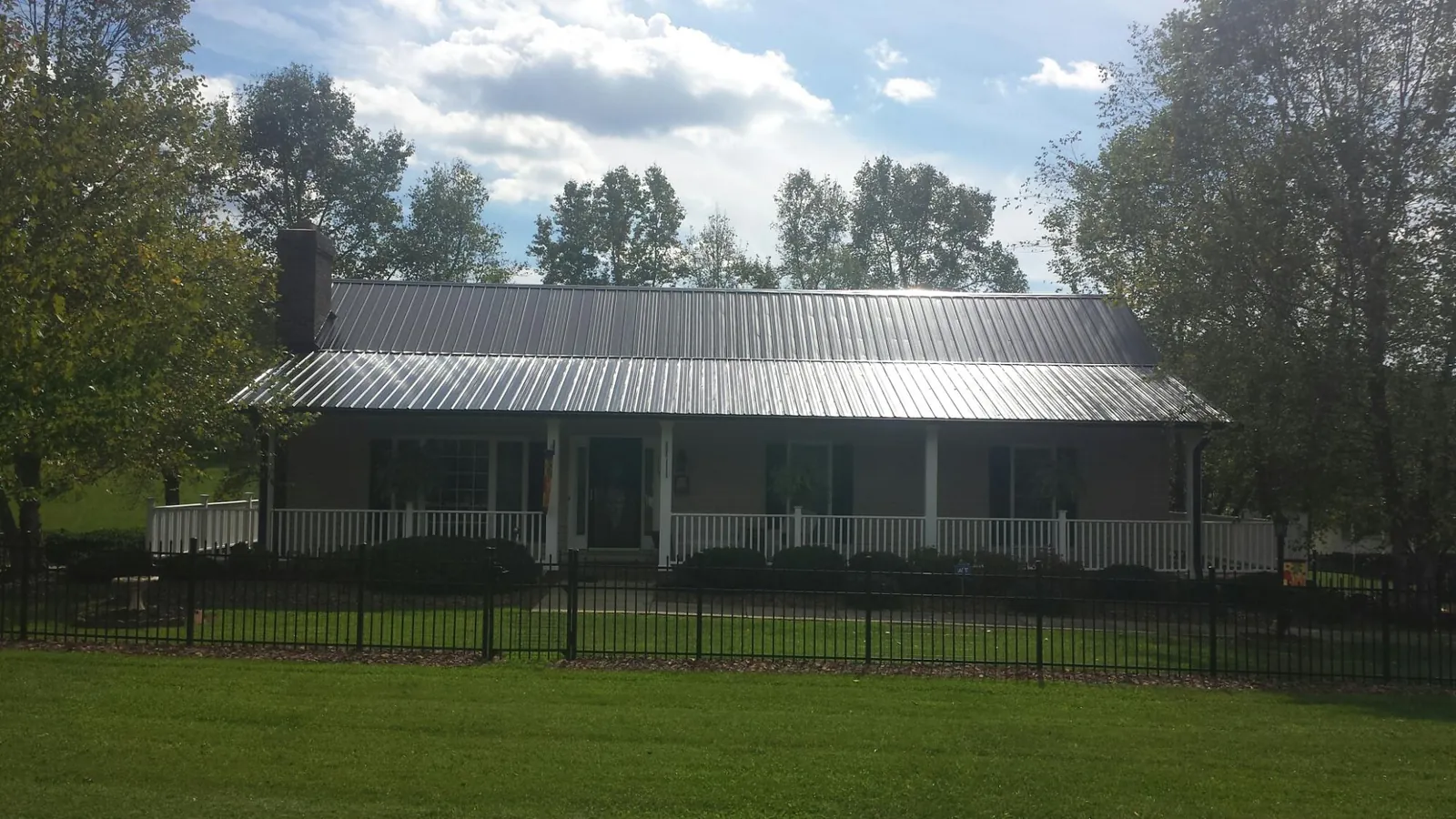 Gray metal roof on a brick ranch with a full width front porch — Gutter Guard Installation work by our crew in Lake Helen