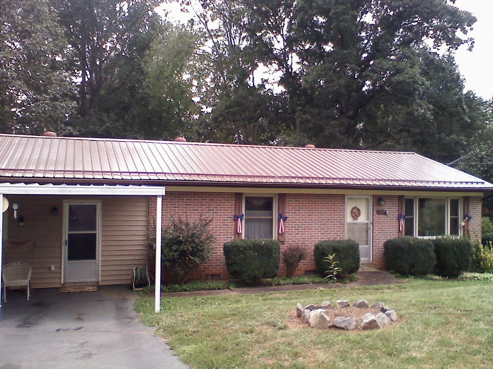 Bronze metal roof and carport on a brick ranch home — Roof Repair work by our crew in Lake Helen
