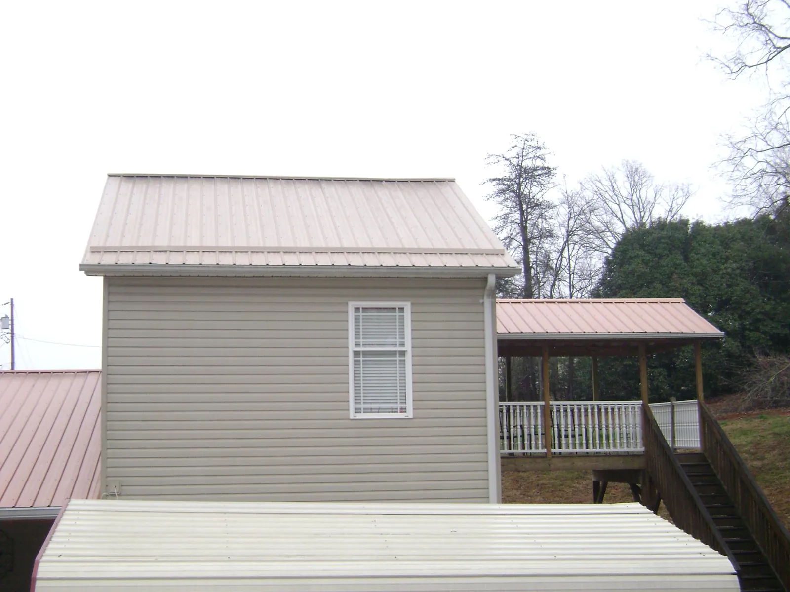 Tan metal roofs on a two story addition and attached porch, from a Roof Replacement job in Lake Helen