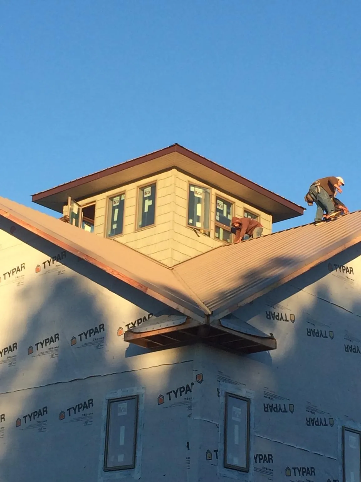 Roofers working around a rooftop cupola on a new metal roof at sunset — Roof Waterproofing in Lake Helen by Roofing Brothers